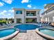 This backyard features a luxurious pool and spa, surrounded by lush landscaping and comfortable lounge chairs at 1281 Grand Traverse Pkwy, Reunion, FL 34747