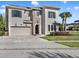 A stunning two-story stucco home boasts a brick accent wall, well-manicured lawn, and a paved driveway at 1281 Grand Traverse Pkwy, Reunion, FL 34747