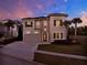 Charming two-story home featuring stone accents, a paver driveway, and exterior lighting at 1281 Grand Traverse Pkwy, Reunion, FL 34747