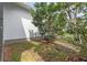 A view of the side of the house showing the landscaped backyard with trees and green grass at 13759 Mommsen Ave, Orlando, FL 32827