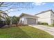 Detached two-car garage with a gray door, surrounded by a well-maintained lawn and landscaping at 13759 Mommsen Ave, Orlando, FL 32827