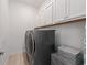 Laundry room with modern washer and dryer, overhead cabinets, and wood-style tile flooring at 13759 Mommsen Ave, Orlando, FL 32827