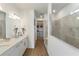 Hallway view of a modern bathroom featuring double sinks, a glass shower, and access to a walk-in closet at 13916 Destin Beach Ln, Orlando, FL 32827