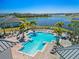 Stunning community pool area with palm trees, lounge chairs, and a beautiful lake view at 13916 Destin Beach Ln, Orlando, FL 32827