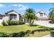 Inviting front yard featuring a well-maintained lawn, mature palm trees, and an attached two-car garage at 14136 Magnolia Glen Cir, Orlando, FL 32828