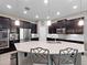 Modern kitchen features an island with seating, stainless steel appliances, dark wood cabinets, and stylish pendant lighting at 14554 Winter Stay Dr, Winter Garden, FL 34787