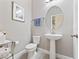 Modern powder room features a pedestal sink, decorative mirror, and neutral wall color at 14554 Winter Stay Dr, Winter Garden, FL 34787