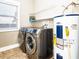 A laundry room equipped with front loading washer and dryer, water heater and shelving at 1513 Pinecrest Pl, Orlando, FL 32803