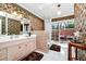 Bright bathroom with vanity, neutral tiles, unique wall paper, and glass door to atrium at 1532 Lake Shore Dr, Orlando, FL 32803