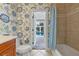 Bathroom with floral wallpaper, a shower with blue curtains, and a doorway view of the outdoor pool at 1600 Barcelona Way, Winter Park, FL 32789