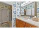 Bathroom featuring floral wallpaper, a large mirror, wood cabinets, and an open door to a bath and shower area at 1600 Barcelona Way, Winter Park, FL 32789