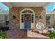 Inviting front porch with brick floor, columns, and a door adorned with a wreath, exuding warmth at 1600 Barcelona Way, Winter Park, FL 32789