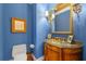 Stylish powder room with blue wallpaper, a gold-framed mirror, sconces, and vintage-style sink at 1600 Barcelona Way, Winter Park, FL 32789