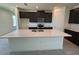 Well-lit kitchen features large island with sink, dark cabinets, and stainless steel appliances at 1995 Iorio St, St Cloud, FL 34771