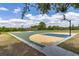 Full basketball court with two hoops surrounded by lush greenery under a bright blue partly cloudy sky at 2523 Water Valley Dr, St Cloud, FL 34771
