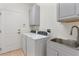 Functional laundry room with washer, dryer, sink, white cabinets, and a door to the outside at 2523 Water Valley Dr, St Cloud, FL 34771