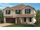 Charming two-story home with a tan exterior, brown roof, a 2-car garage and nicely manicured lawn at 3385 Sanctuary Dr, Clermont, FL 34714