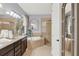 Luxurious bathroom featuring double sinks, a large soaking tub, and a glass enclosed shower at 3707 Paradiso Cir, Kissimmee, FL 34746