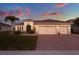 Beautiful home exterior boasts a brick driveway, lush lawn, and an attached two-car garage at 3707 Paradiso Cir, Kissimmee, FL 34746
