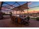 Relaxing screened-in patio with dining set, spa, and scenic water view at dusk at 3707 Paradiso Cir, Kissimmee, FL 34746