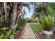Landscaped backyard with walkway, lush lawn, and tropical foliage, creating a private oasis at 4991 Tangerine Ave, Winter Park, FL 32792