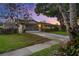 Single-story home with a well-manicured lawn, driveway, mature trees, and an attached two-car garage with a screen door at 4991 Tangerine Ave, Winter Park, FL 32792