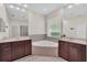 Bright bathroom features a soaking tub, tile surround, and double vanity with mirrors at 6613 Duncaster St, Windermere, FL 34786