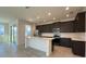 Modern kitchen featuring stainless steel appliances, dark cabinetry and a white island with seating at 7020 Rolling Leaf Dr, Groveland, FL 34736