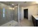 Main bath with large glass shower, tile walls, and double vanity with dark cabinets at 7020 Rolling Leaf Dr, Groveland, FL 34736