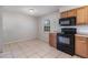 Kitchen area featuring tile floors, wooden cabinets, black microwave and oven at 7906 Arabian Pl, Orlando, FL 32818