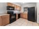 Functional kitchen featuring tile floors, wooden cabinets, and black appliances at 7906 Arabian Pl, Orlando, FL 32818
