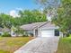 Single-story home with a two-car garage, neutral paint, trimmed bushes, and a concrete driveway at 11512 Grand Bay Blvd, Clermont, FL 34711