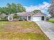 Single-story house with a two-car garage, neutral paint, mature trees, and manicured landscaping at 11512 Grand Bay Blvd, Clermont, FL 34711
