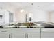 Close-up of a kitchen island featuring a stainless steel sink, marble counters, and white cabinetry at 11512 Grand Bay Blvd, Clermont, FL 34711