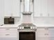 Contemporary kitchen features stainless steel range hood, white cabinetry, and marble backsplash at 11512 Grand Bay Blvd, Clermont, FL 34711