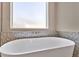 Bright bathroom featuring soaking tub with silver mosaic tiling and frosted window offering natural light at 1312 Vassar St, Orlando, FL 32804