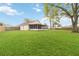 Well-maintained backyard with ample green space, surrounded by a wooden fence, and showcasing the screened lanai at 14026 Eckard Ct, Orlando, FL 32826