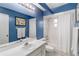 Well-lit bathroom with white cabinets and vanity, blue walls and shower with curtain at 14026 Eckard Ct, Orlando, FL 32826