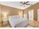 Bedroom with a ceiling fan, white bed linens, and view to an en-suite bathroom at 14026 Eckard Ct, Orlando, FL 32826