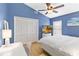 Bright blue bedroom featuring a ceiling fan, TV, closet and light wood floors at 14026 Eckard Ct, Orlando, FL 32826