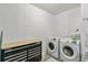 Modern laundry room with white washer and dryer, black tool chest and white brick walls at 14026 Eckard Ct, Orlando, FL 32826