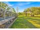 Large green backyard, screened pool area, pond in the background, and surrounding trees at 141 Greenfield Rd, Winter Haven, FL 33884