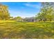 Expansive backyard with a well-maintained lawn and the back of the house with a screened pool at 141 Greenfield Rd, Winter Haven, FL 33884