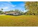 Large, grassy backyard with mature trees and view of a screened-in porch attached to the house at 141 Greenfield Rd, Winter Haven, FL 33884