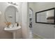 Cozy half-bathroom featuring a unique pedestal sink, decorative mirror, and neutral finishes at 14467 Prunningwood Pl, Winter Garden, FL 34787