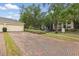 Paver driveway leading to a two-car garage, set in a community with mature trees at 14467 Prunningwood Pl, Winter Garden, FL 34787