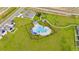 Aerial shot of the community pool and playground area with palm trees and ample green space at 1811 Silverbell Loop, Haines City, FL 33844