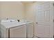 Bright laundry room featuring white appliances and a white door at 2011 Oakbend Dr, Eustis, FL 32726