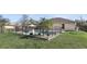 Back exterior view of in-ground pool with tropical landscaping, black fence, and backyard play set at 2662 Haulover Blvd, Deltona, FL 32738
