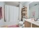 Bathroom featuring a shower with curtain, toilet, sink, wooden shelf, and a pink rug at 2804 Polvadero Ln # 107, Orlando, FL 32835